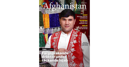 Bilden visar ett tidningsomslag till tidningen Afghanistan-Nytt. På bilden syns en man klädd i vita kläder och en röd, broderad väst. Han tittar in i kameran och bakom honom syns tyger i olika färger.