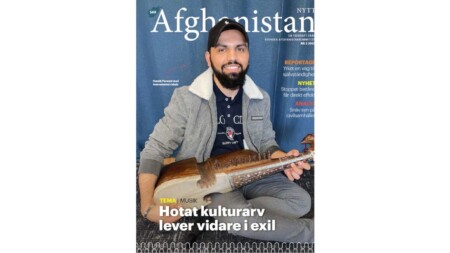 Bild på omslaget på tidningen, man sitter med instrumentet rubab framför ett blått skynke.