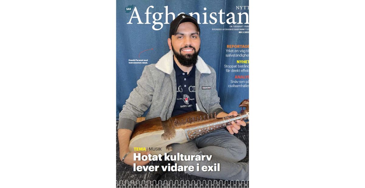 Bild på omslaget på tidningen, man sitter med instrumentet rubab framför ett blått skynke.