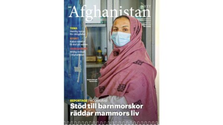 Tidningen Afghanistan-nytts omslag, med en bild på en barnmorska i rosa sjal och vitt munskydd vid ett medicinskåp. Rubriker på bilden: Stöd till barnmorskor räddar mammors liv, Tema: Hemlig kamp för rättigheter, Nyhet: Kabul riskerar få slut på vatten, Verksamhet: Möjlig nystart i Afghanistan
