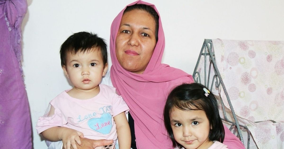 Leende mamma håller om två små barn.