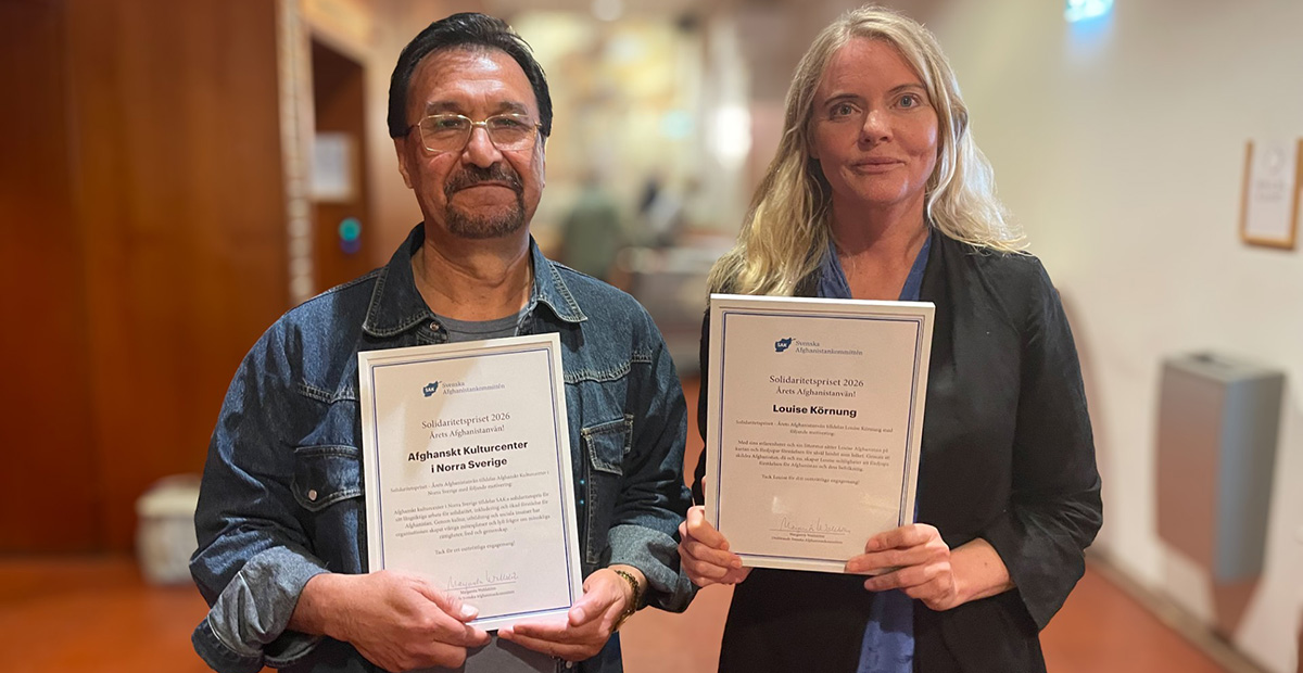 En kvinna och en man står i en korridor med varsitt diplom.