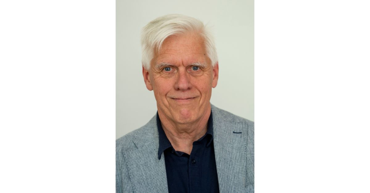 Porträttbild på man i svart skjorta och grå¨kavaj.